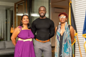 Nastassia Rambarran, Rondell Trim, and Nia Brathwaite smiling together at the CariFLAGS reception in Kingston, Jamaica.